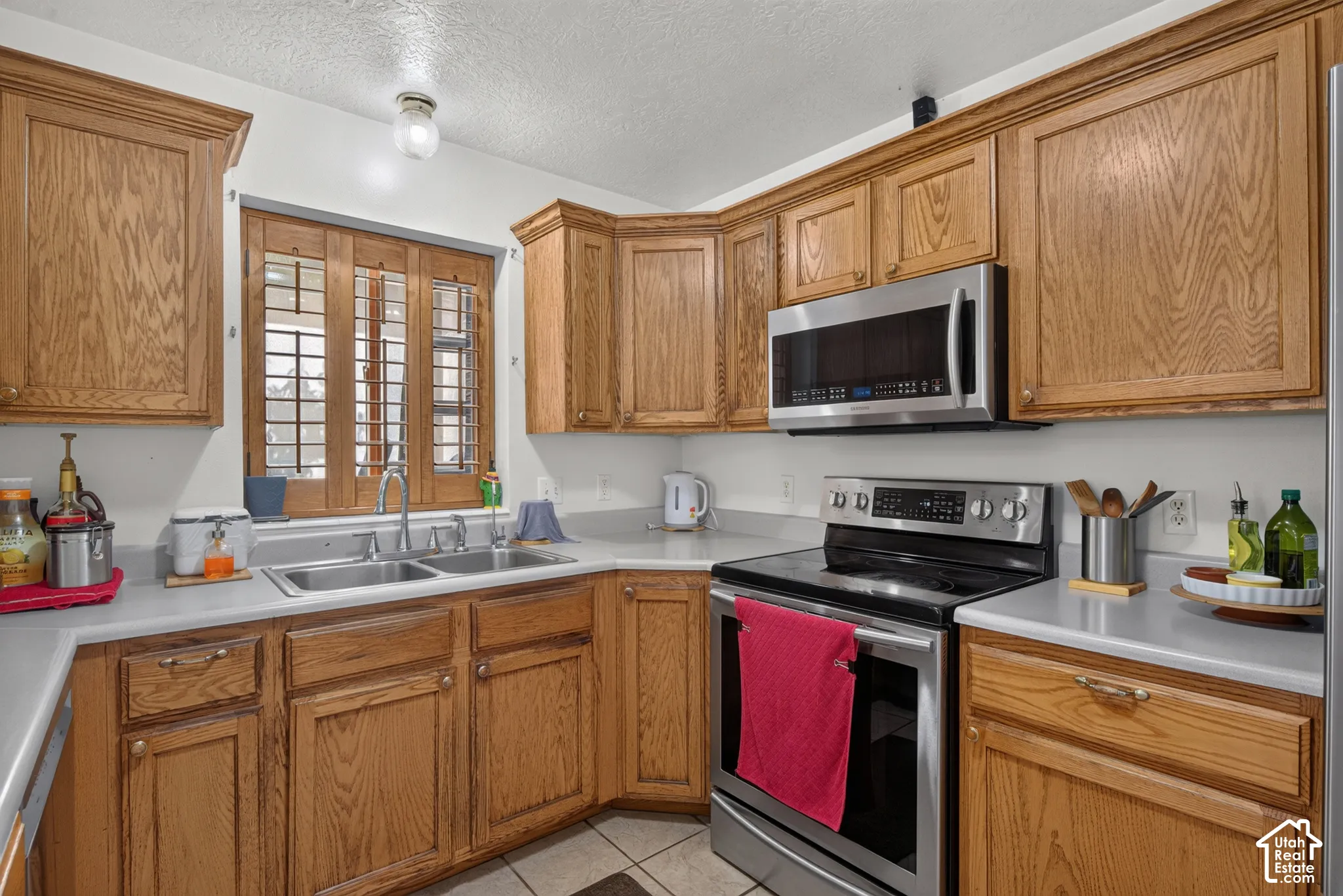 Wood-finish cabinetry, stainless steel appliances, dual basin sink, and a built-in microwave