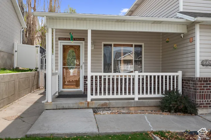 Covered front porch with white railings, brick accent siding, and light-colored horizontal siding