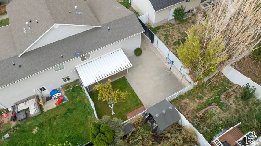 Expansive backyard featuring a concrete patio, covered awning, and a storage shed