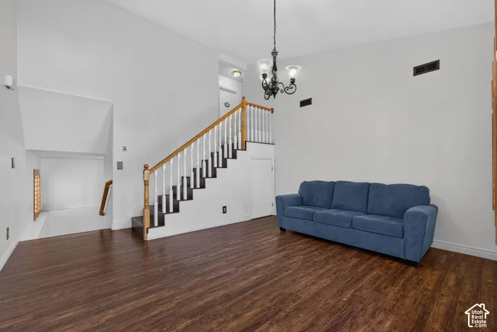 High ceilings with a decorative chandelier, wood-finish flooring, and a staircase with a wood handrail