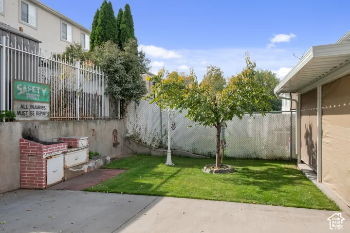 Expansive concrete patio with a lush green lawn and mature tree
