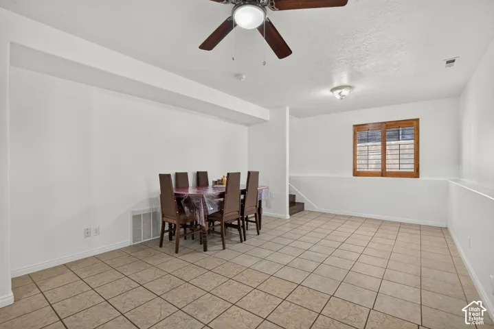 Recessed ceiling with wood-finish ceiling fan, square tile flooring, wood-framed window with integrated blinds, and built-in steps