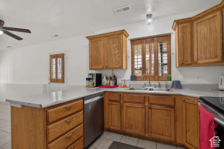 Wood-finish cabinetry paired with light countertops, stainless steel dishwasher, and a dual basin sink
