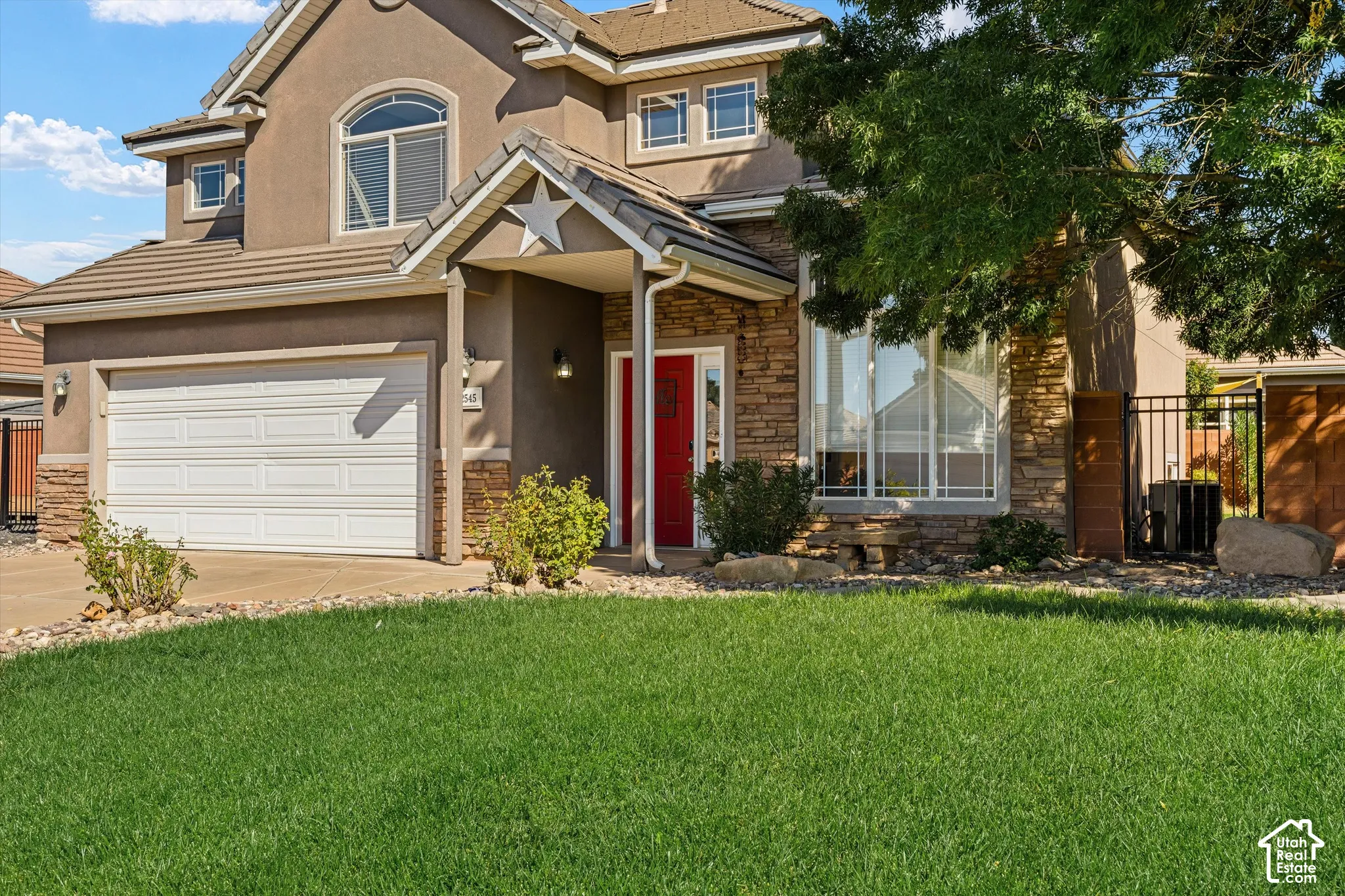 Exterior featuring a two-car garage, stucco siding, and stone accents