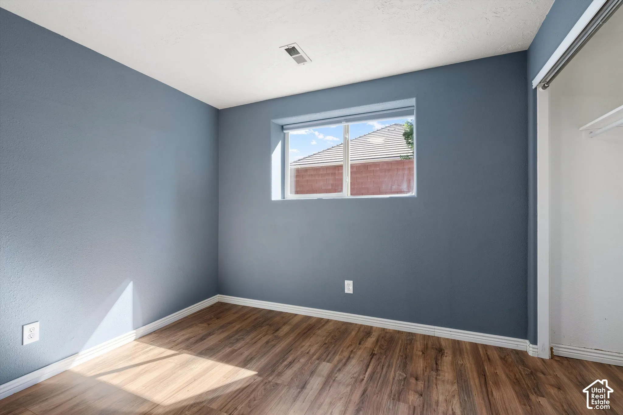 Wall-to-wall wood-finish flooring, white window trim, and white painted trim