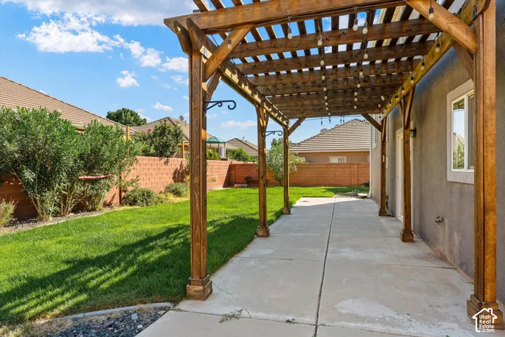 Spacious backyard featuring a wood pergola, concrete patio, and a manicured lawn