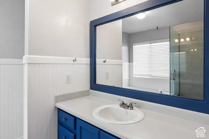 White beadboard wainscoting, a vessel sink, and a blue framed mirror
