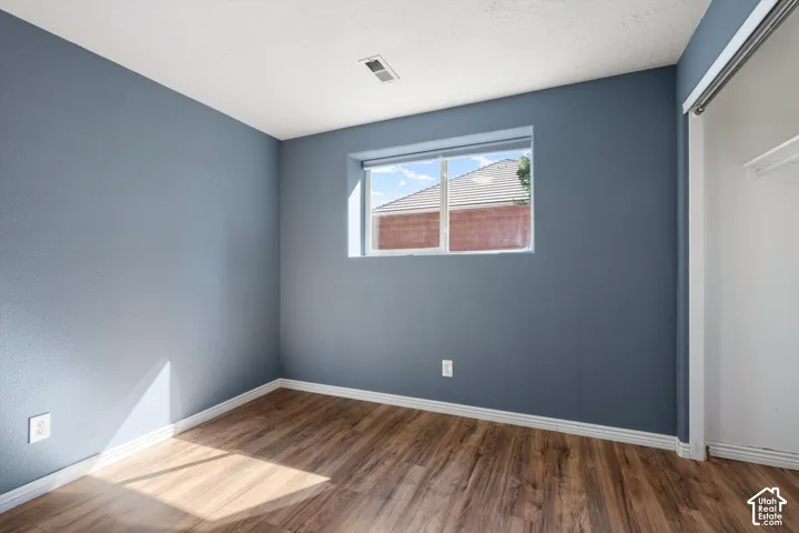 Wall-to-wall wood-finish flooring, white window trim, and white painted trim