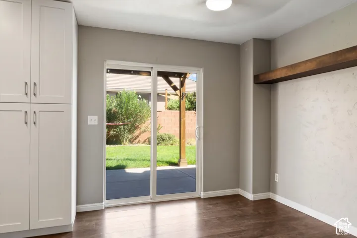 Full-height cabinetry, wood-finish flooring, sliding glass door, exposed wood beam, and outdoor patio
