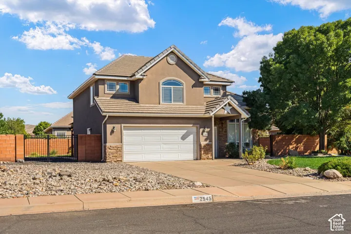 Stucco exterior with stone accents, arched window, attached two-car garage, and tiled roof