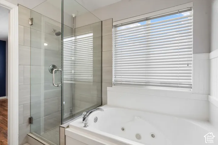 Glass-enclosed shower with a rainfall showerhead, alongside a jetted soaking tub