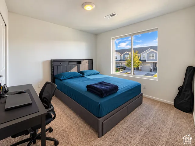 Carpeted room featuring a large window, integrated ceiling light fixture, and a white interior door