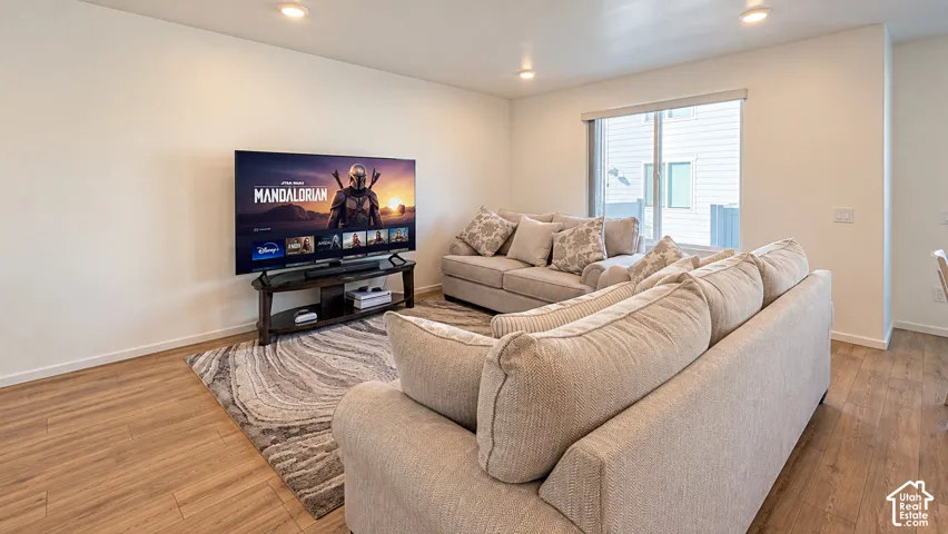Recessed lighting, wood-finish flooring, white walls, and a large window with blinds