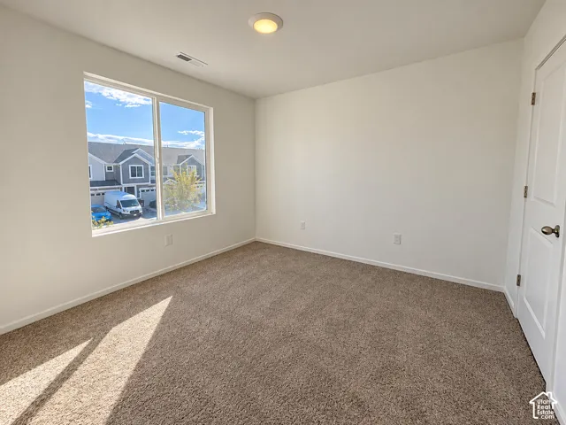 Neutral wall color, carpet flooring, flush mount lighting, white trim, and a window providing natural illumination