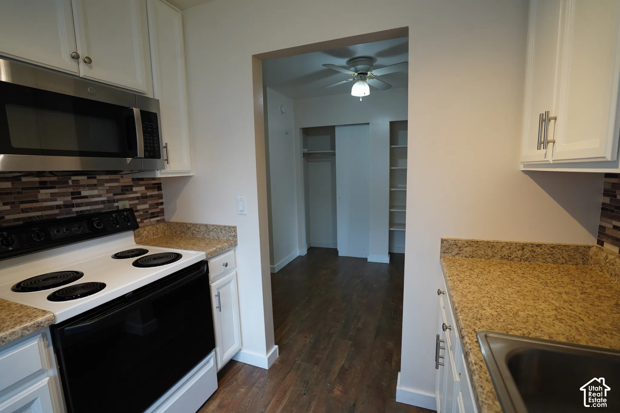 Kitchen featuring white cabinetry, a stainless steel microwave, and granite-look countertops