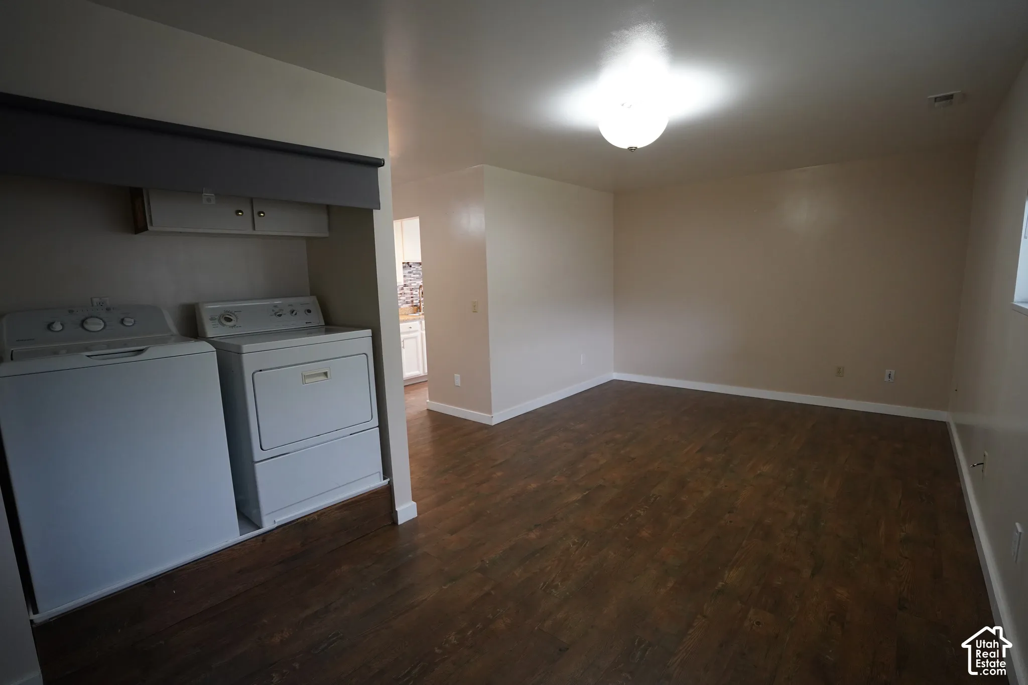 Laundry area with built-in cabinetry, wood-finish flooring, and overhead lighting