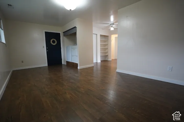 Wood-finish flooring throughout, with a built-in shelving unit, and a ceiling fan in the background