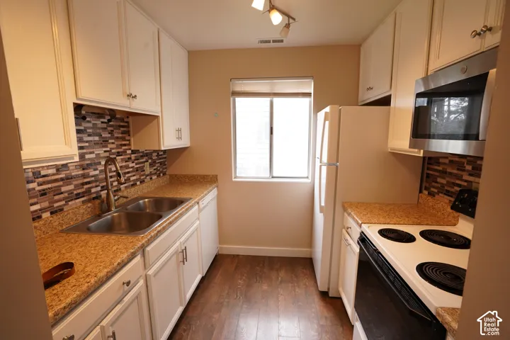 Kitchen featuring white cabinetry, a dual basin stainless steel sink, a mosaic tile backsplash, and wood-finish flooring