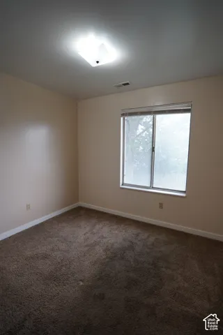 Wall-to-wall carpeting, neutral wall color, and a flush-mount ceiling light