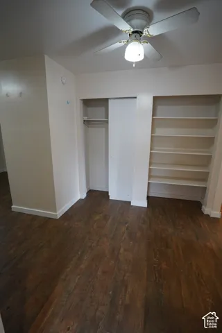 Wood-finish flooring, built-in shelving, sliding closet doors, and a ceiling fan with integrated lighting