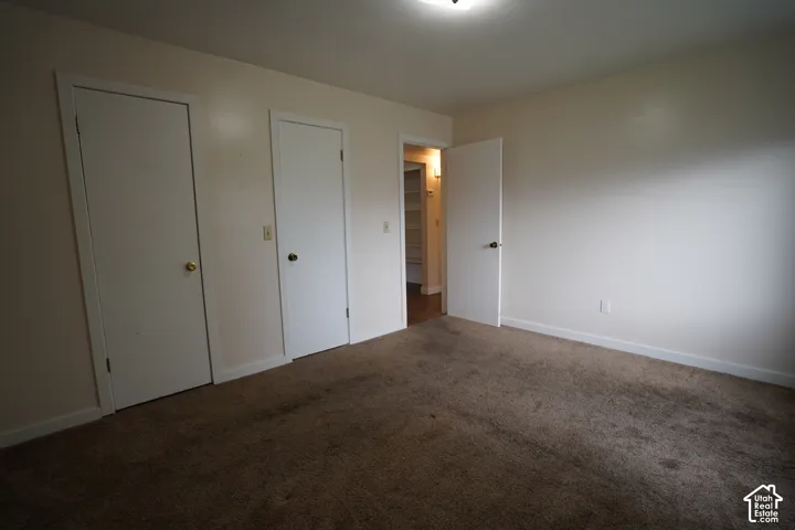 Carpeted flooring, two white doors with doorknobs, and a ceiling-mounted light fixture