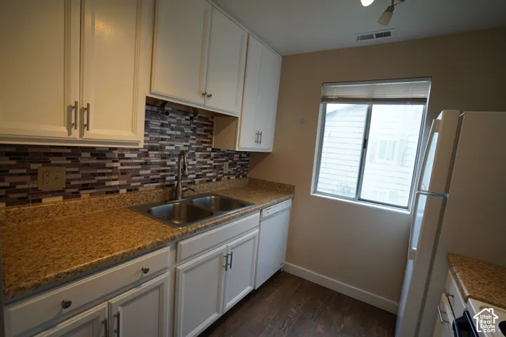 White cabinetry with brushed nickel hardware, a multi-tone tile backsplash, and a double basin stainless steel sink