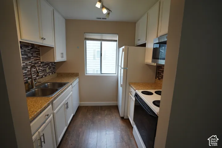 Kitchen featuring white cabinetry, wood-finish flooring, a mosaic tile backsplash, double basin sink, and track lighting