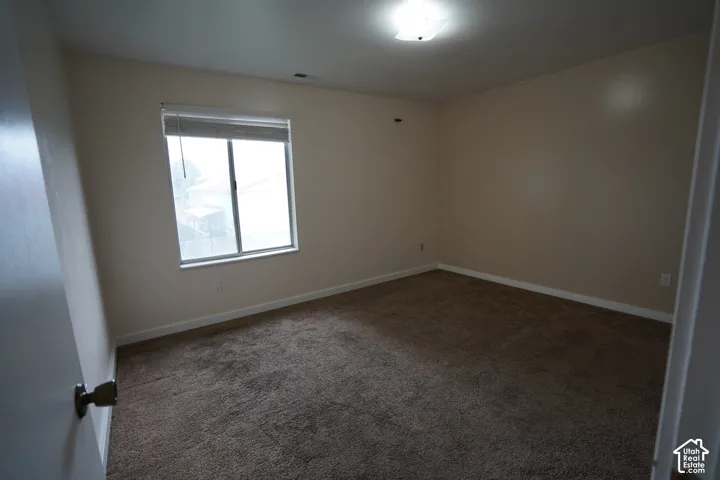 Neutral wall paint, brown carpet flooring, and a single window with blinds