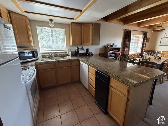 Kitchen featuring wood cabinetry, granite-style countertops, tile flooring, and integrated appliances