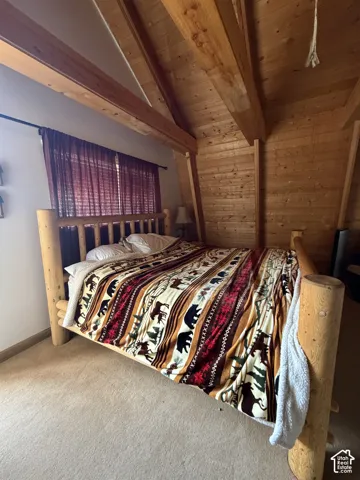 Wood-paneled vaulted ceiling with exposed beams, wood-finish wall panels, and carpeted flooring