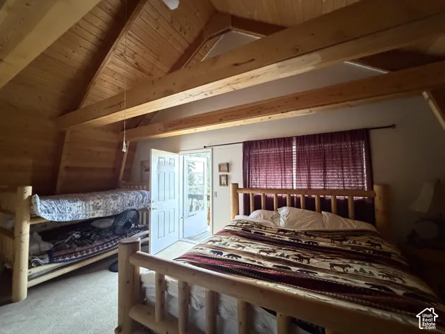 Vaulted wood-paneled ceiling with exposed beams, wood-paneled walls, and carpet flooring