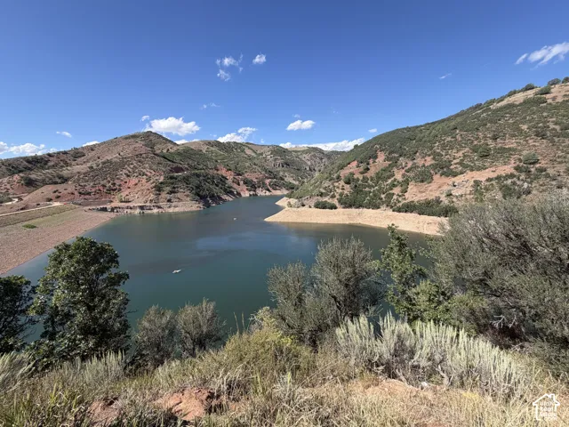 Expansive water frontage with surrounding mountainous terrain, natural landscaping, and a clear water body