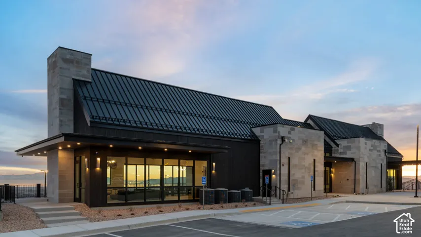 Modern architectural design featuring stone and dark siding, a black metal roof, and large glass windows