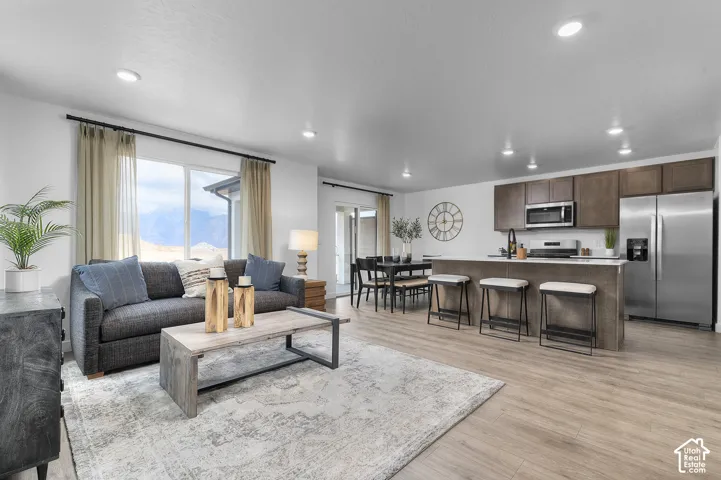 Spacious open-concept living area featuring wood-finish flooring, recessed lighting, and large windows