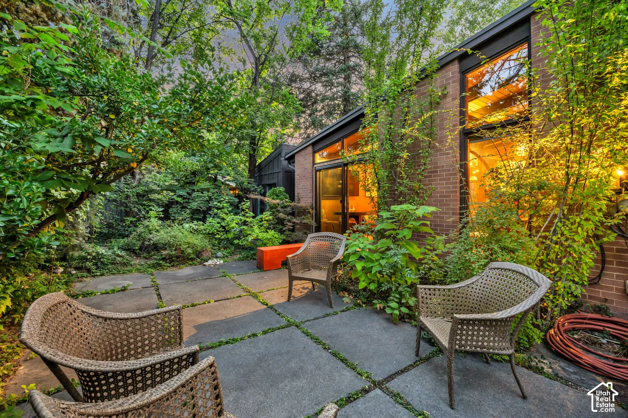Brick exterior with expansive windows, surrounded by lush landscaping and mature trees