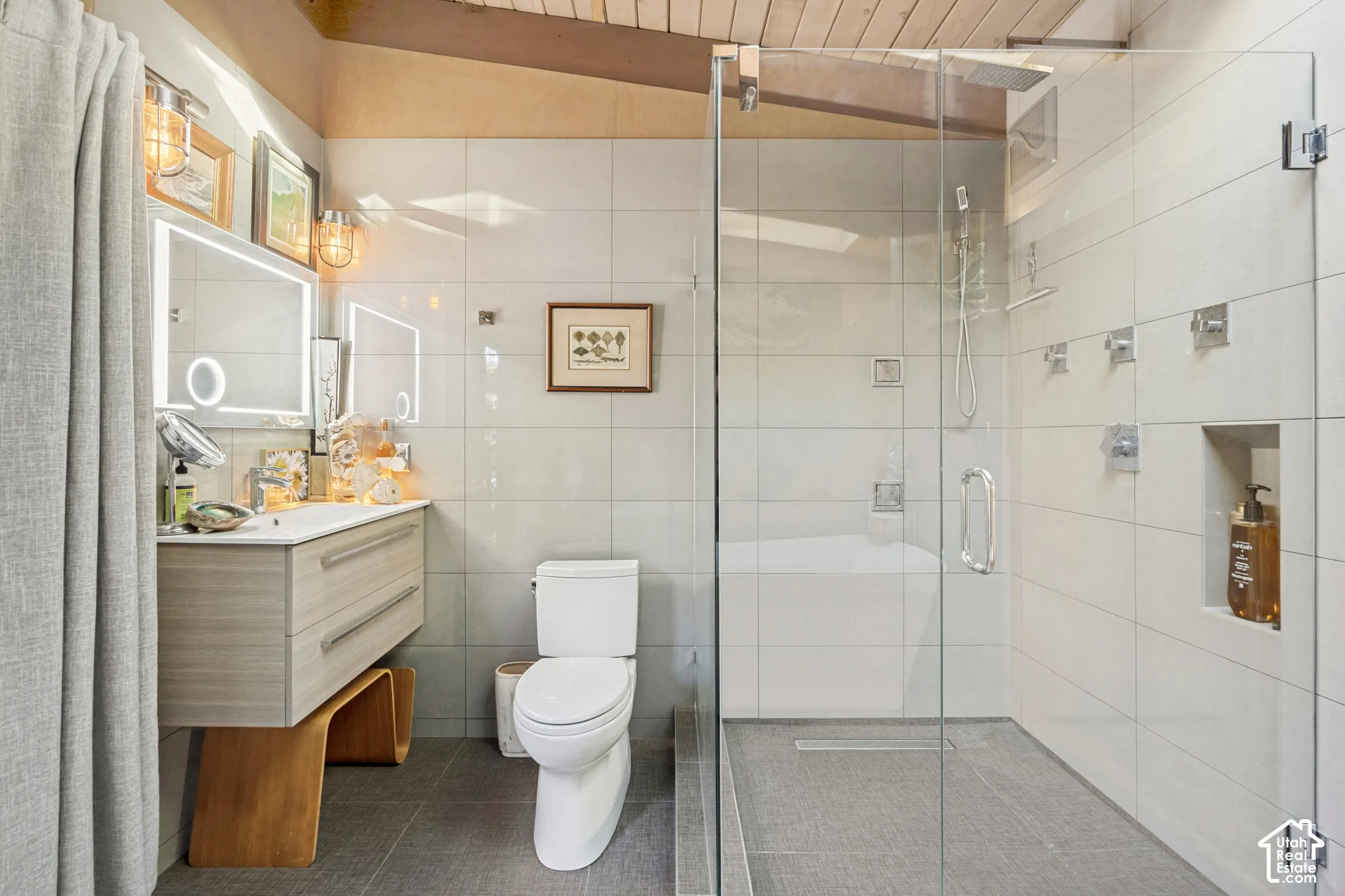 Contemporary bathroom featuring a floating vanity with integrated sink, a glass-enclosed shower, a built-in shower niche, and ceiling-mounted wood beams