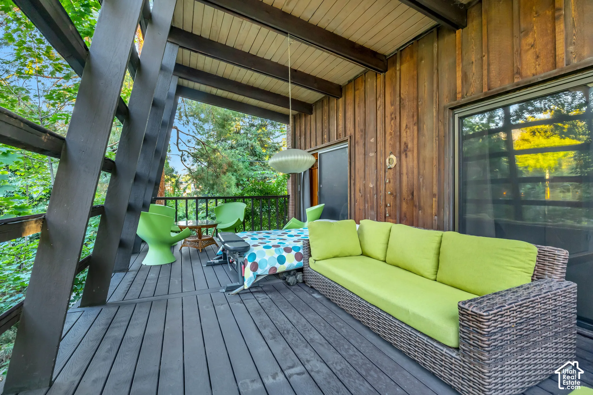 Expansive outdoor deck featuring dark wood-finish flooring, exposed wood beams, wood paneling, and a large glass sliding door