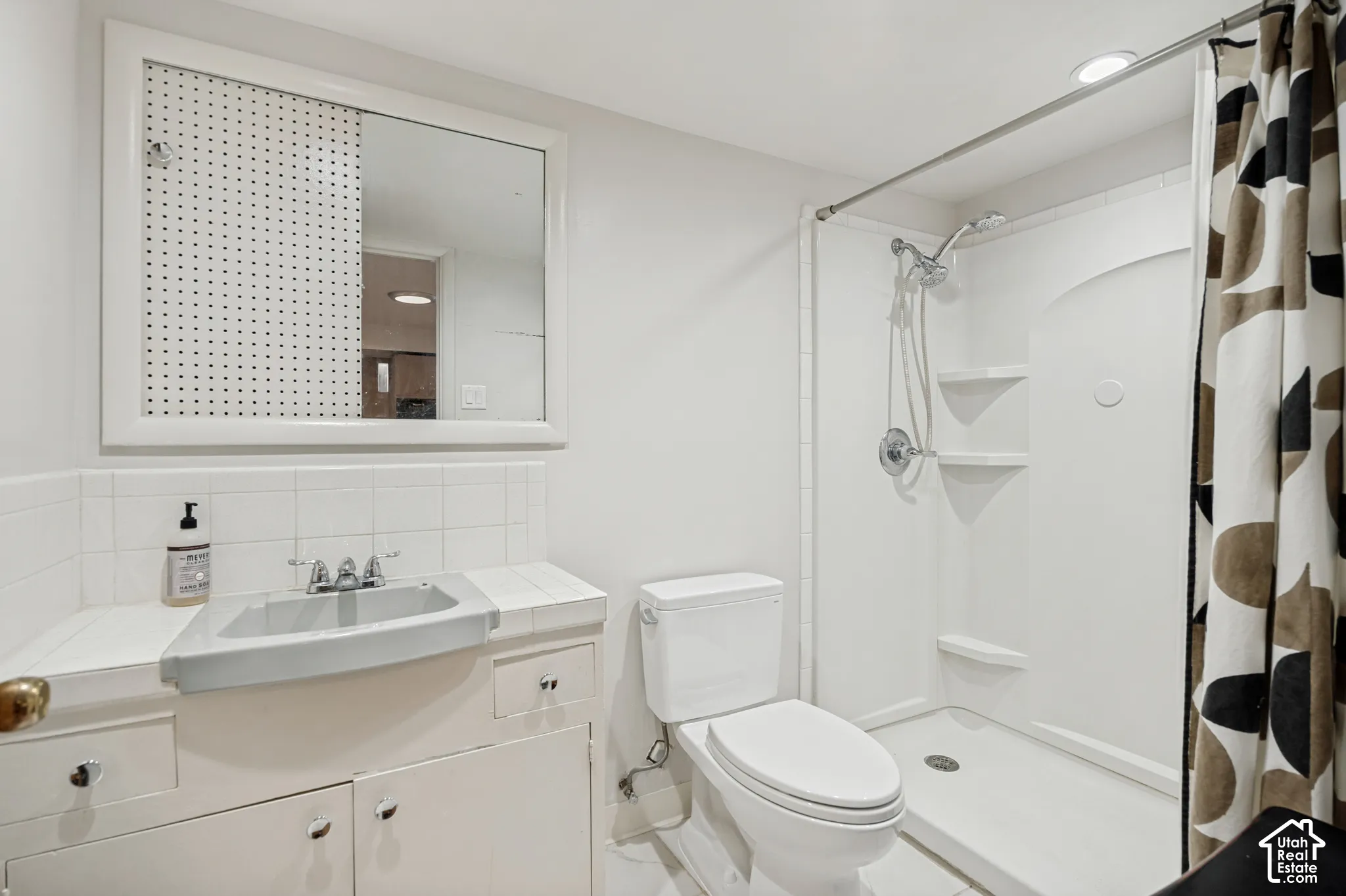 White tile countertop with an integrated sink, built-in vanity cabinetry, and a framed mirror