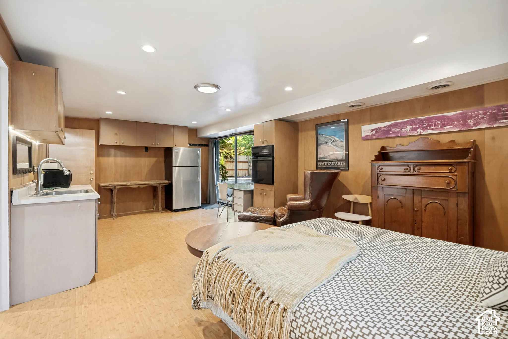 Wood paneling throughout, built-in cabinetry, stainless steel refrigerator, recessed lighting, and a glass sliding door