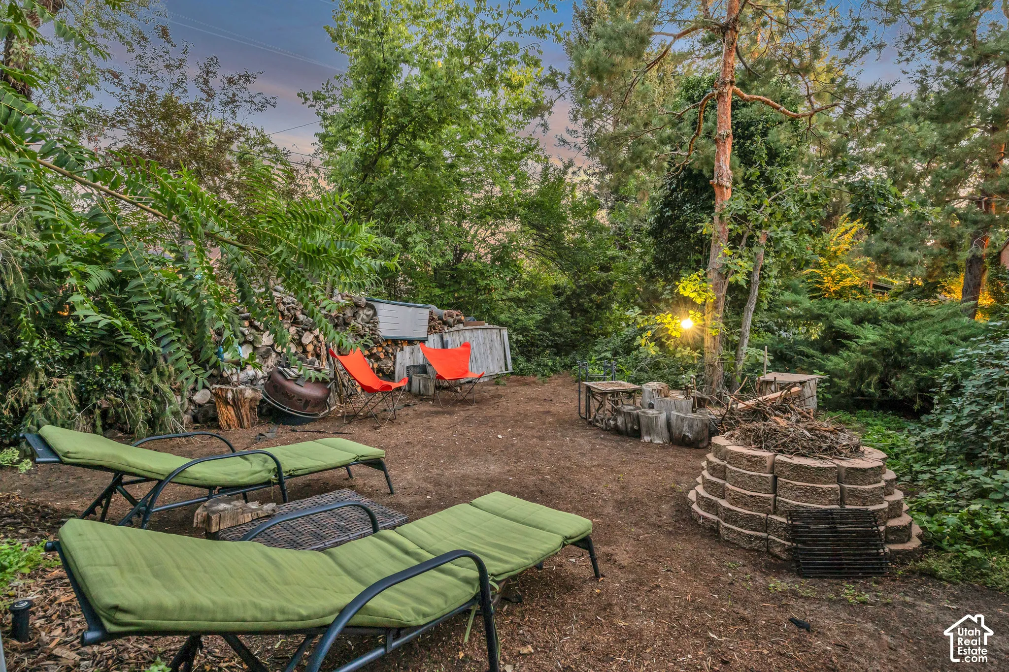 Outdoor space with mature trees, a built-in fire pit, and wood storage