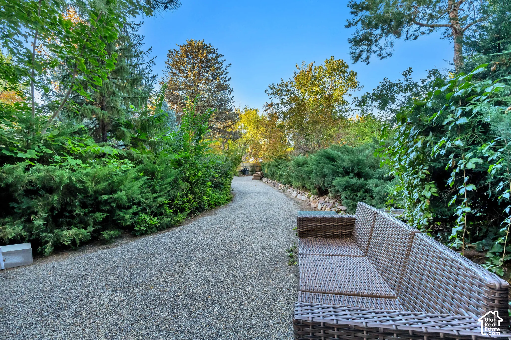 Gravel pathway with lush perimeter landscaping and mature trees