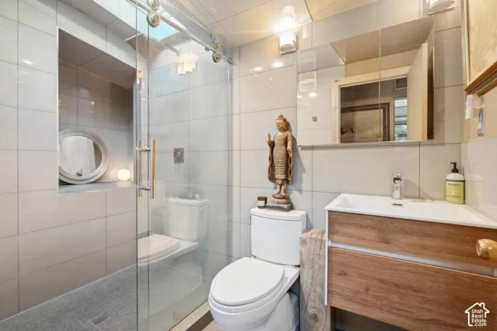 Glass-enclosed shower with a recessed niche, wood-finish vanity with an integrated sink, wall-mounted mirrored medicine cabinet, and tile flooring