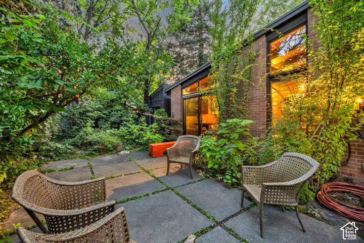 Brick exterior with expansive windows, surrounded by lush landscaping and mature trees