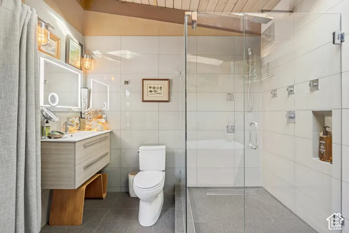 Contemporary bathroom featuring a floating vanity with integrated sink, a glass-enclosed shower, a built-in shower niche, and ceiling-mounted wood beams