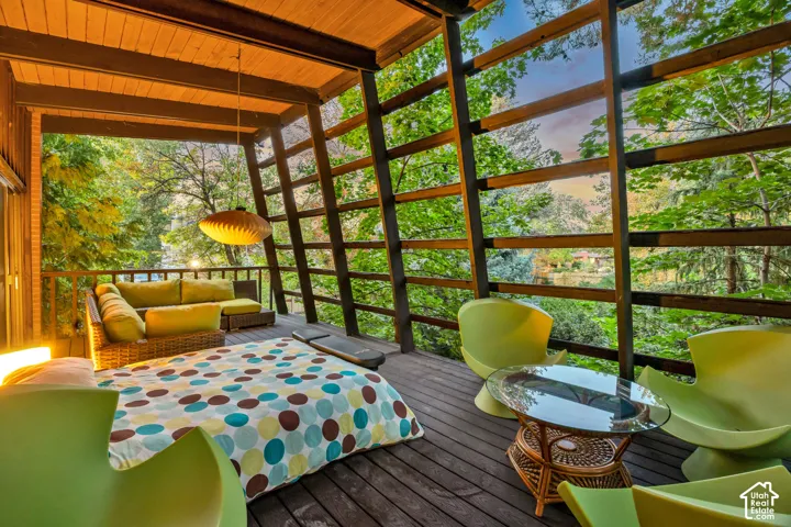 Expansive outdoor deck with wood-finish flooring, featuring a slatted wood railing, and a suspended lighting fixture