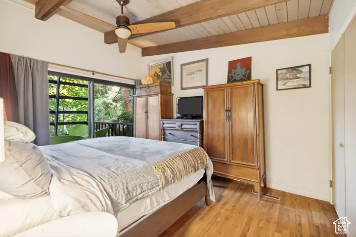 Hardwood flooring, wood-beamed ceiling, ceiling fan with light fixture, sliding glass doors, and a private balcony
