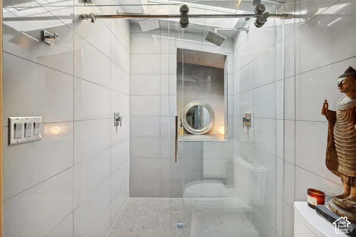 Glass-enclosed shower with a rainfall showerhead, recessed niche, and integrated lighting