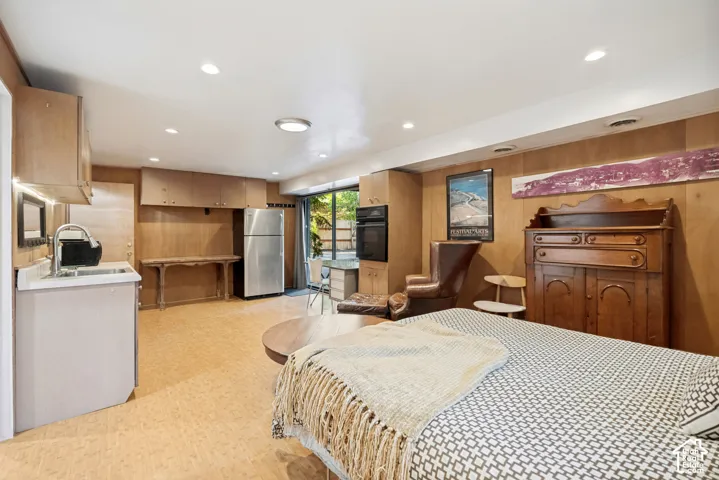 Wood paneling throughout, built-in cabinetry, stainless steel refrigerator, recessed lighting, and a glass sliding door
