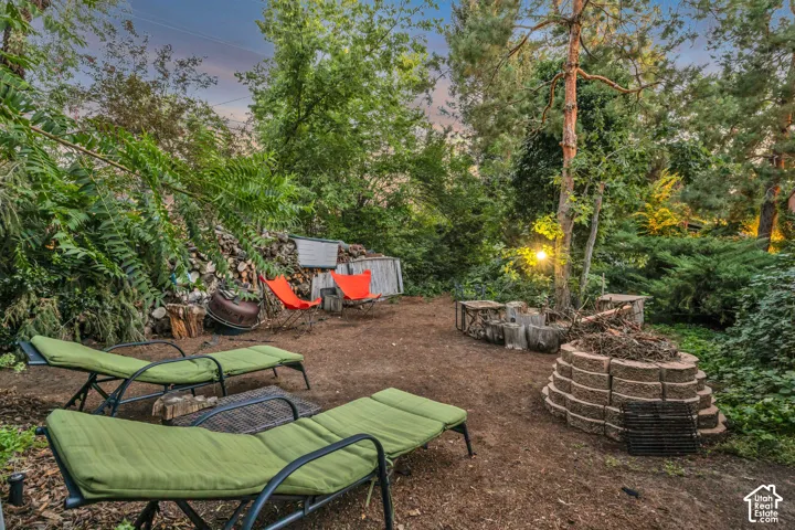 Outdoor space with mature trees, a built-in fire pit, and wood storage