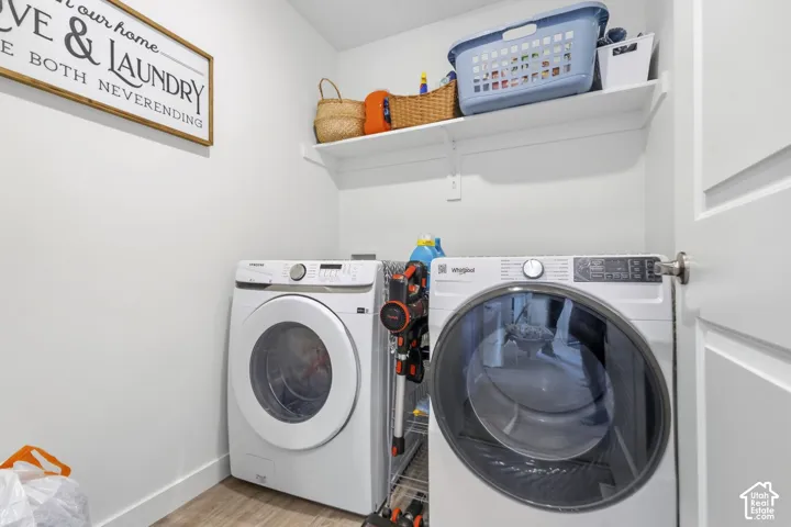 Dedicated laundry area featuring white walls, a white floating shelf, and wood-finish flooring